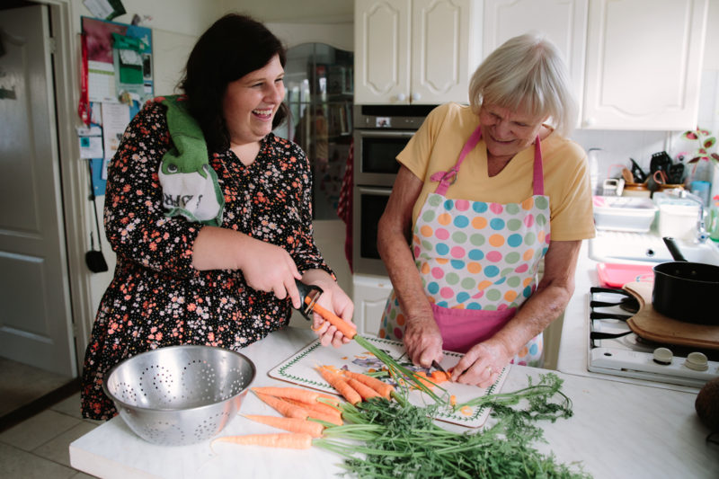 Two people preparing carrots for cooking